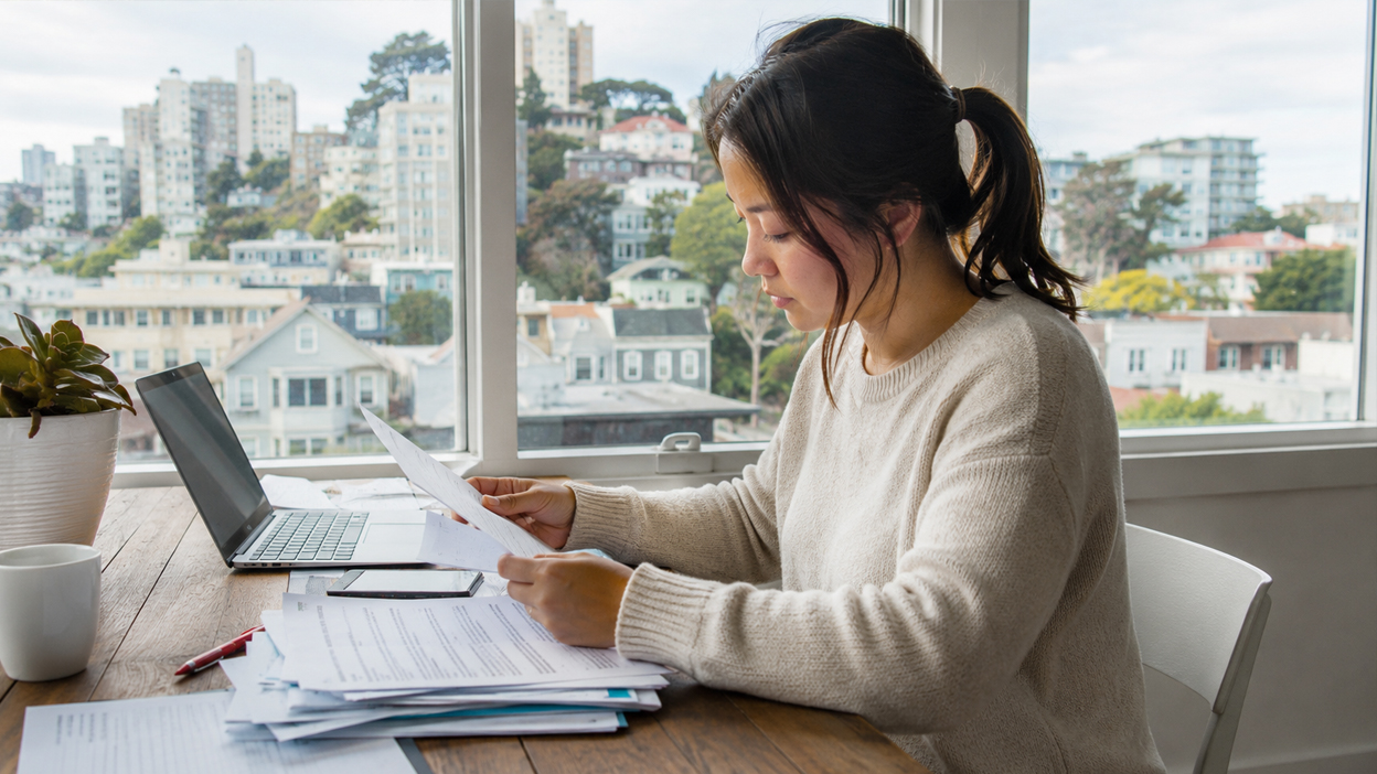 Practical Paperwork and Setup Tasks After Moving Resident reviewing moving paperwork at a home desk with a San Francisco neighborhood visible through the window.